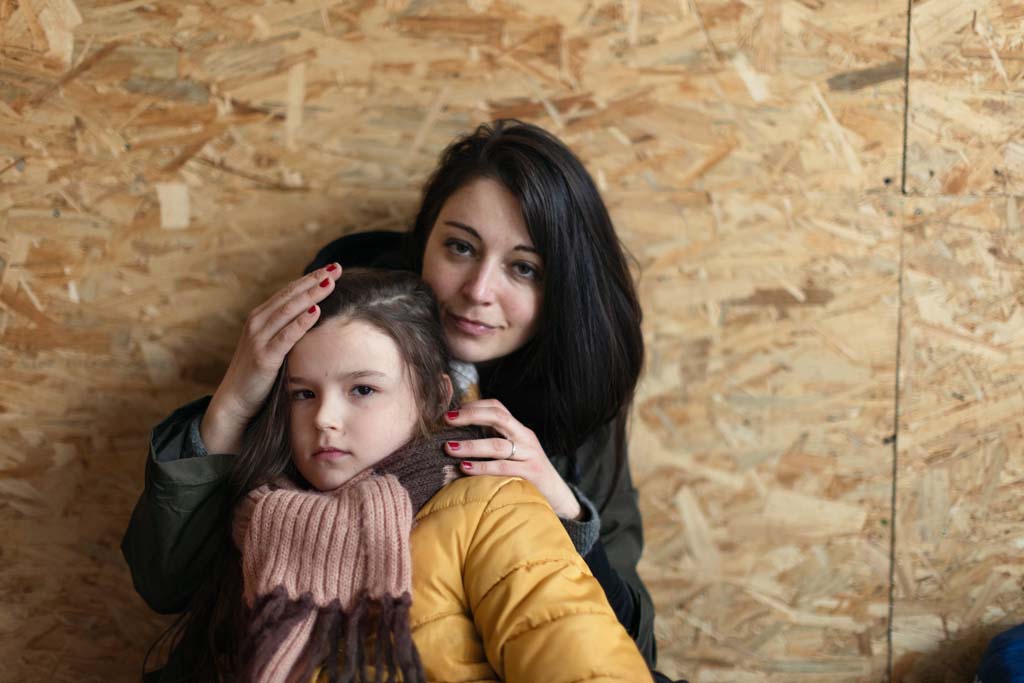 Ukrainian war refugees in temporary shelter and help center, little girl with her mother.